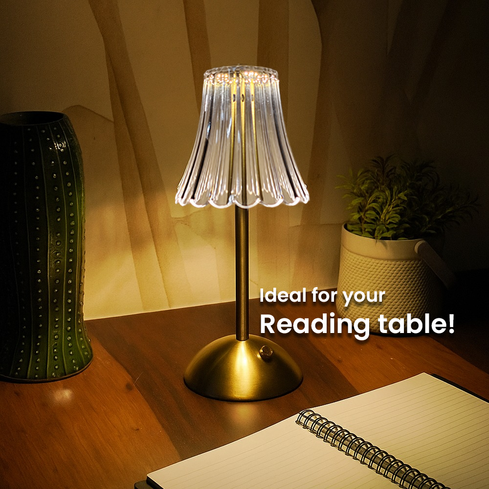Table lamp on a wooden table with a notebook and plant, ideal for reading.